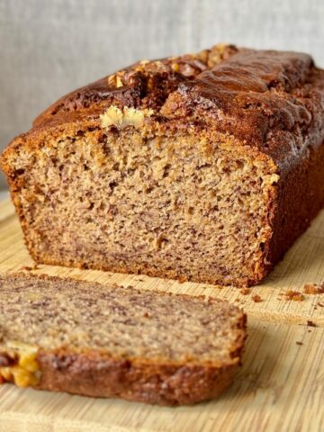 sliced banana coffee cake, showing a beautifully moist crumb and topped with walnuts