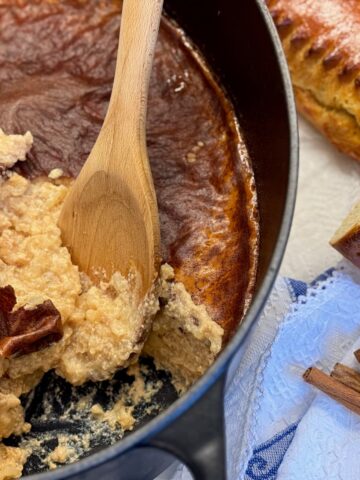 large pot with a baked rice pudding covered in a thick caramel skin, spooning out a creamy mixture underneath with cinnamon and a traditional French Fallue brioche